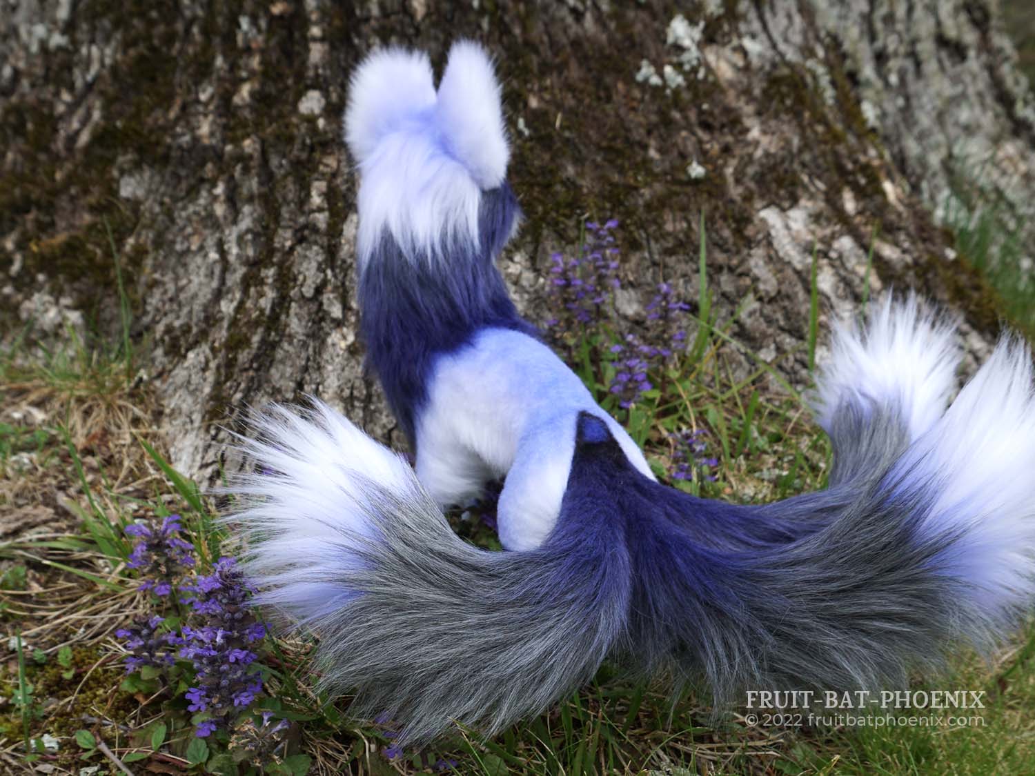 back view of a lavender, white, and silver grey three-tailed kitsune